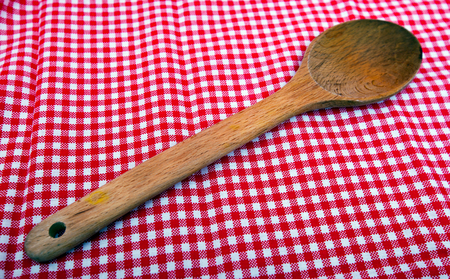 Wooden spoon close up on a red and white tableclothの写真素材
