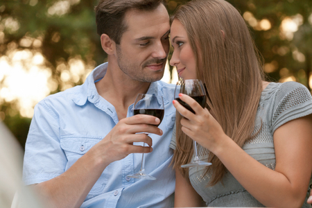 Loving young couple toasting red wine in parkの写真素材