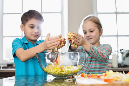 Brother and sister preparing salad in kitchenの写真素材