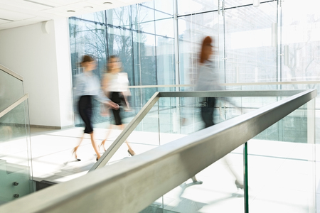 Blurred motion of businesswomen walking at office hallwayの写真素材