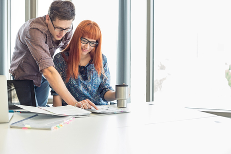 Businesspeople analyzing file together at desk in creative officeの写真素材