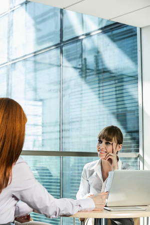 Businesswomen discussing at table in officeの写真素材