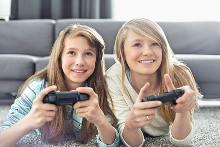 Sisters playing video games in living roomの写真素材