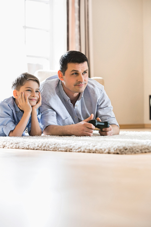 Father and son playing video game on floor at homeの写真素材
