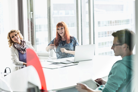 Happy businesspeople sitting at desk in creative officeの写真素材