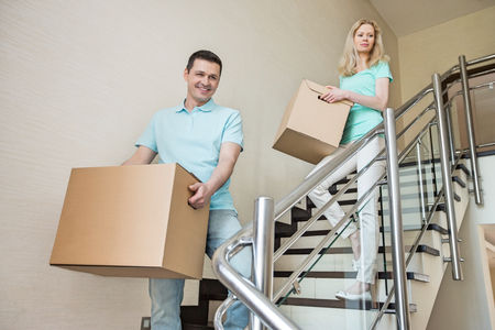 Couple carrying cardboard boxes while moving down steps at new homeの写真素材