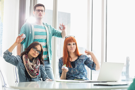 Angry businesspeople throwing paper balls in creative officeの写真素材