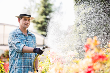 Man watering plants outside greenhouseの写真素材