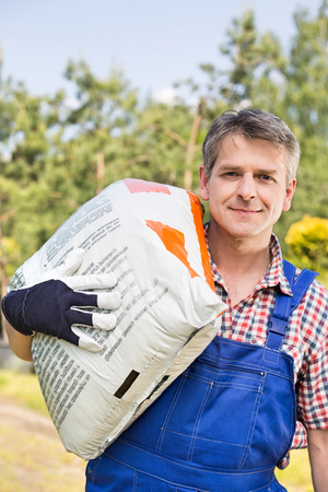 Portrait of confident gardener carrying sack in plant nurseryの写真素材