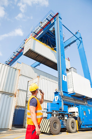 Worker using walkie-talkie in shipping yardの写真素材