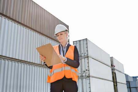 Female worker reading clipboard in shipping yard