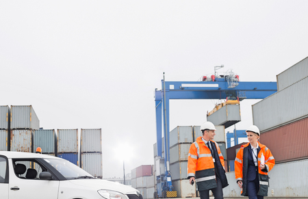 Workers conversing while walking in shipping yardの写真素材