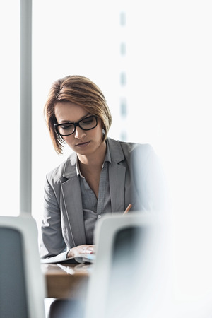 Young businesswoman writing at desk in officeの写真素材