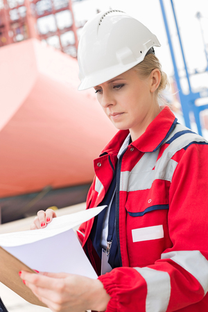 Female engineer reading documents in shipping yardの写真素材