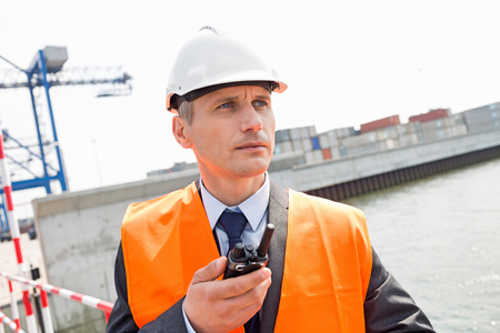Middle-aged man using walkie-talkie in shipping yardの写真素材