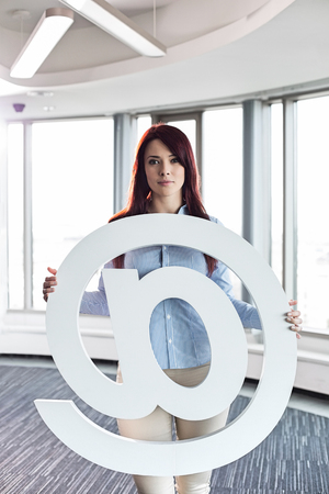Portrait of beautiful businesswoman holding at sign in creative officeの写真素材