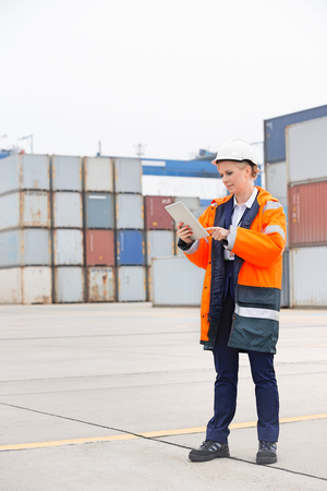 Full-length of female engineer using tablet computer in shipping yardの写真素材