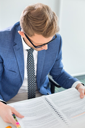 Creative businessman reading file at desk in officeの写真素材