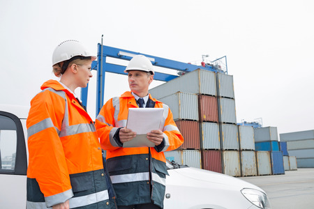 Workers conversing in shipping yardの写真素材