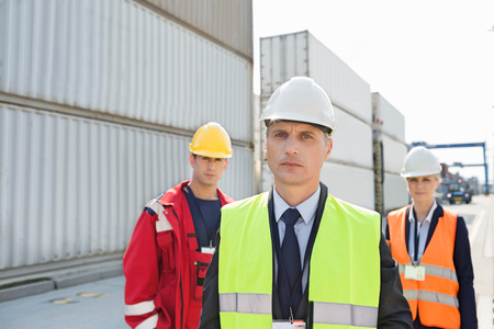 Team of confident workers in shipping yard