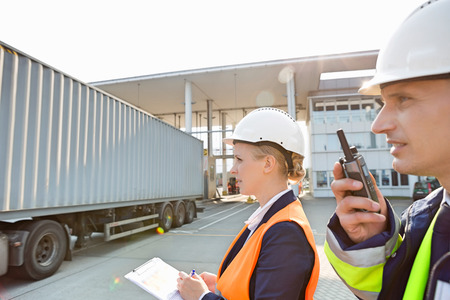 Male and female workers working in shipping yardの写真素材