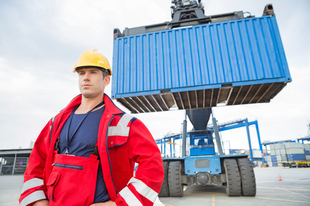 Confident male worker standing in front of freight vehicle at shipyardの写真素材