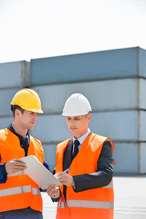 Worker taking sign of supervisor on clipboard in shipping yardの写真素材