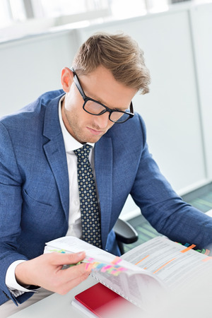 Businessman reading file at desk in creative officeの写真素材