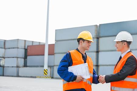 Workers shaking hands in shipping yardの写真素材