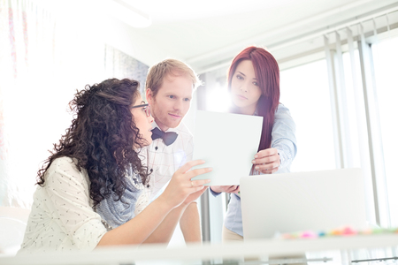 Businesspeople discussing over photograph in creative officeの写真素材