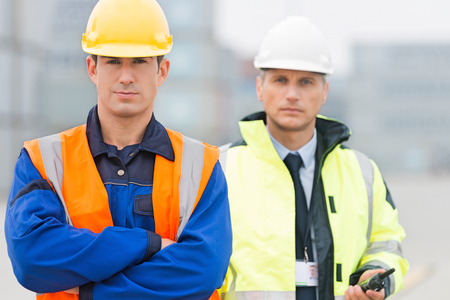 Portrait of confident worker standing with coworker in shipping yardの写真素材