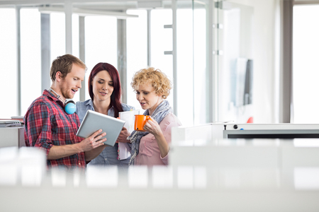 Businessman with female colleagues discussing over tablet PC in officeの写真素材
