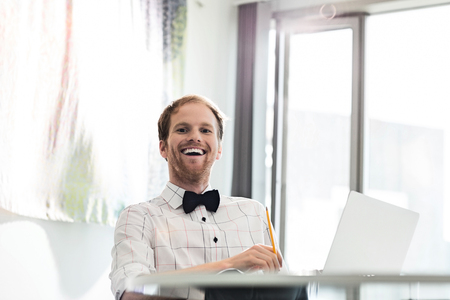 Cheerful businessman sitting at desk in creative officeの写真素材