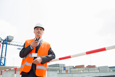 Middle-aged man using walkie-talkie in shipping yardの写真素材