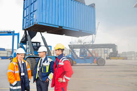 Workers discussing in shipping yardの写真素材