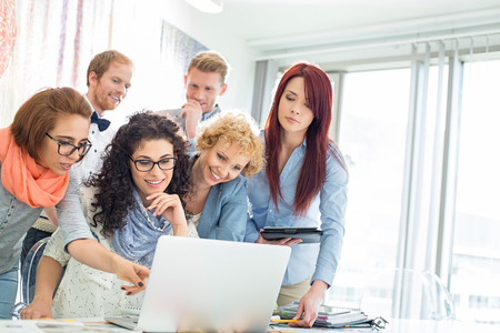 Group of businesspeople using laptop at desk in creative officeの写真素材