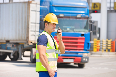 Mid adult man using walkie-talkie in shipping yardの写真素材