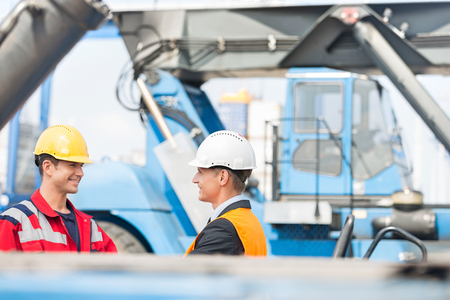 Workers shaking hands in shipping yardの写真素材