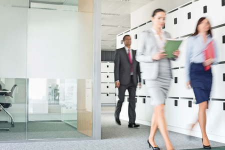 Blurred view of businesswomen walking in officeの写真素材