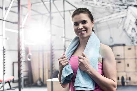 Portrait of happy woman holding towel around neck in crossfit gymの写真素材