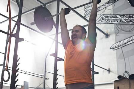 Dedicated man lifting barbell in crossfit gymの写真素材