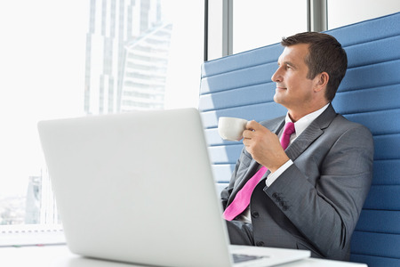 Mature businessman taking coffee break in officeの写真素材