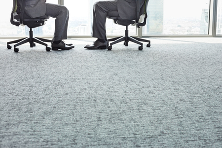 Low section of businessmen sitting on office chairsの写真素材