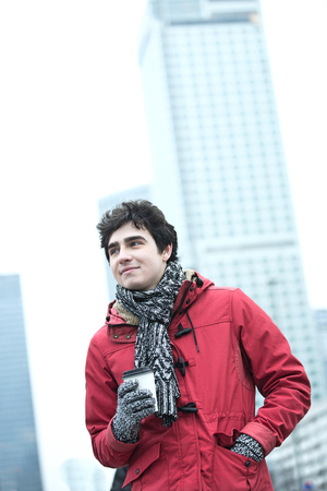 Thoughtful man in warm clothing holding disposable cup outdoorsの写真素材