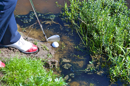 Man chipping ball from water hazardの写真素材
