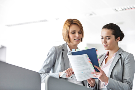 Young businesswomen discussing over book in officeの写真素材