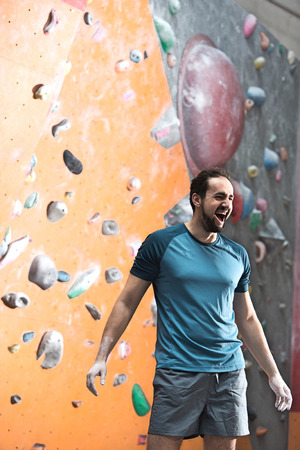 Dedicated man shouting by climbing wall in crossfit gymの写真素材