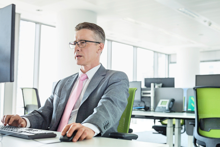 Mature businessman working on computer in officeの写真素材