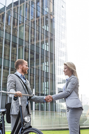 Businesspeople shaking hands outside office buildingの写真素材
