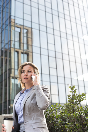 Businesswoman using mobile phone outside office buildingの写真素材
